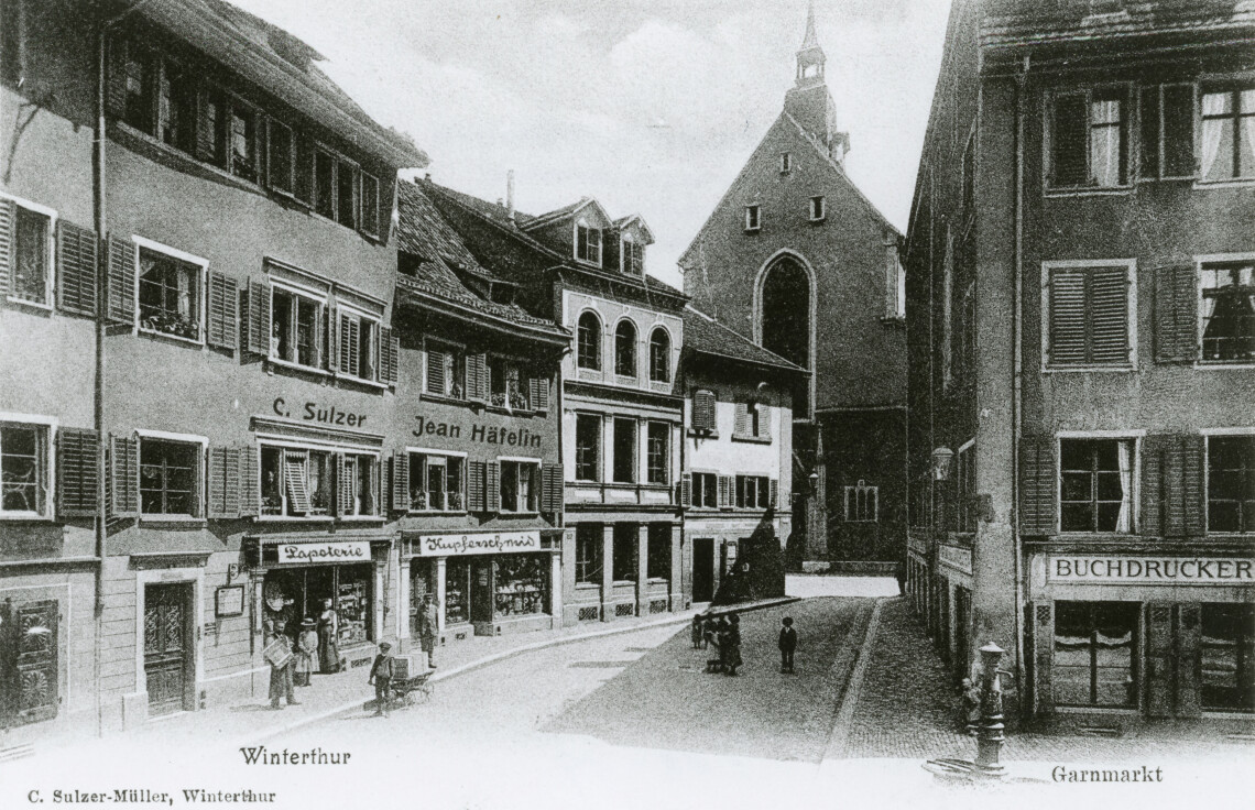 Eine schwarzweiss Postkarte aus dem Jahre 1900 zeigt den Garnmarkt und die Fassade des Problemli Hauptquartiers.
